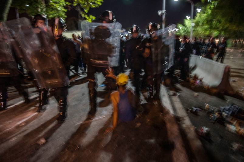 Ett 30-tal poliser omringar den ensamma 14-åriga pojken där han sitter på asfalten. Sedan för de bort honom. Foto: MAGNUS WENNMAN